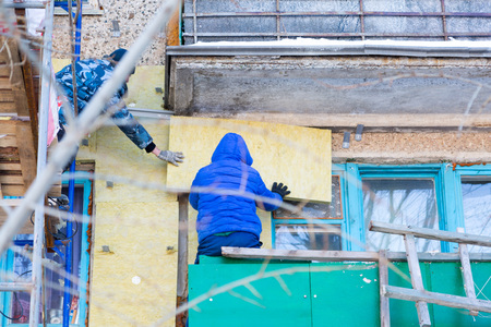 Workers warm and repair the facade of the building.の写真素材