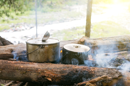 Two pots stand on the fire in the forest. Preparation of food in the trek, two iron pots are heated on an open fire.の写真素材