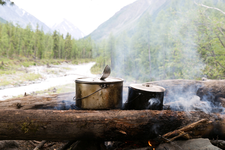 Two pots stand on the fire in the forest. Preparation of food in the trek, two iron pots are heated on an open fire.の写真素材