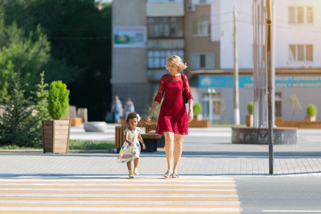 The child runs away from the mother on the pedestrian crossing. A black girl runs along the road from her mother, a danger.の写真素材