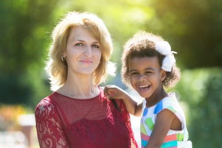 A white woman with a black daughter in her arms. A woman holding a foster-child in her arms.の写真素材