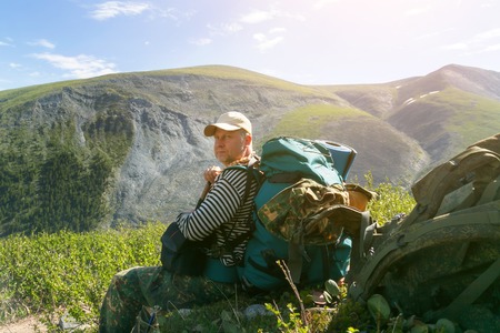 The tourist is resting under a large stone. A man with a backpack.の写真素材