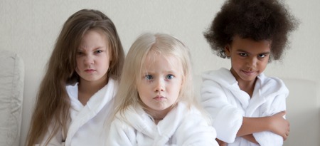 Angry angry women in white coats. Three little girls of different nationalities are offended by their parents.の写真素材