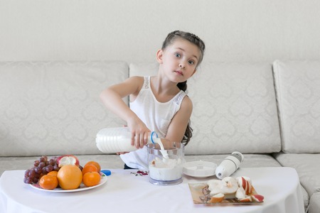 Baby pours milk into a blender. A glass of water for a glass bottle.の写真素材