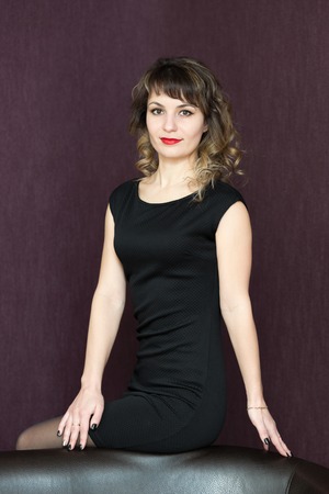 A girl in a black sleeveless dress with curled hair.の写真素材