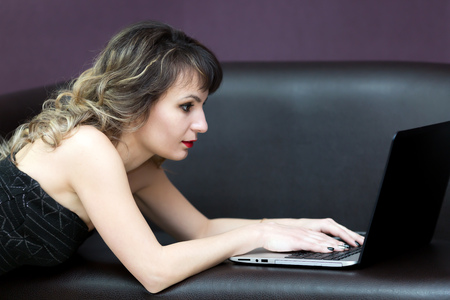 A brunette girl with wavy hair works at a computer.の写真素材