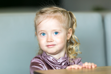 A girl with blue eyes near green grass. Little girl with blue eyes and green grass.の写真素材