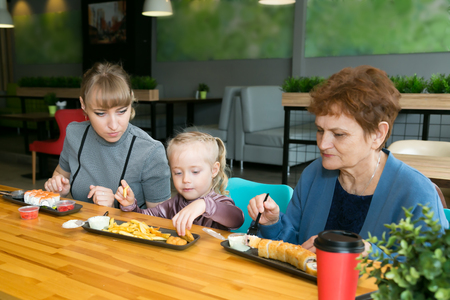 Women of the same family Grandmother, daughter, granddaughter eat in a cafe. Family dinner generation of women.の写真素材