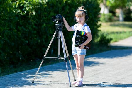 A little girl in headphones with a camera. Portrait of a child with a TV clapper.の写真素材
