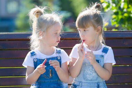 Two girls eat sweets in the park. Two girls have a lot of candy. Sweet lunch at the weekendの写真素材