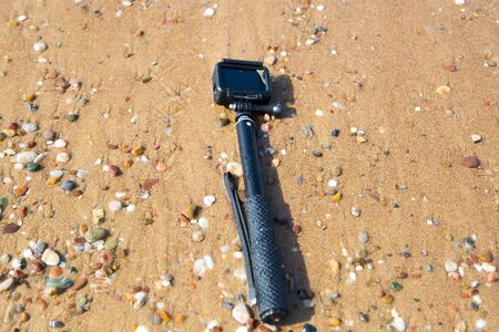 A video camera forgotten by a tourist lies on the beach. Lost action camera on the sea sand.