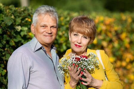 Elderly woman with a bouquet of flowers. A pensioner woman is holding a bouquet of flowers in her...
