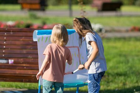 Young friends paint a picture on the street Preschool children, paints draw image on paperの写真素材