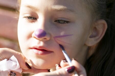 Brother paints on sister's face A little boy puts aqua makeup on face of a 6 year old girlの写真素材