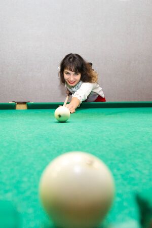 Girl brunette plays billiards. Weekend evening young woman of 30-35 years old beats a cue ball on a billiard ballの写真素材