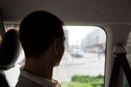 An adult Caucasian male of 35-40 years old is looking out the window while riding in a car.の写真素材