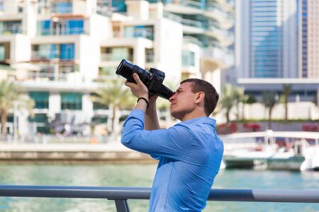 A photographer with a big camera in Dubai. A man in a blue shirt European tourist takes photos on a professional camera.の写真素材