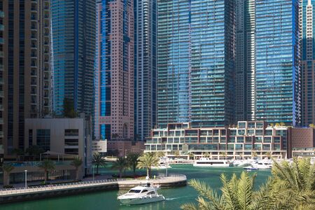 The boat floats along the canal along tall office buildings and residential skyscrapers.の写真素材