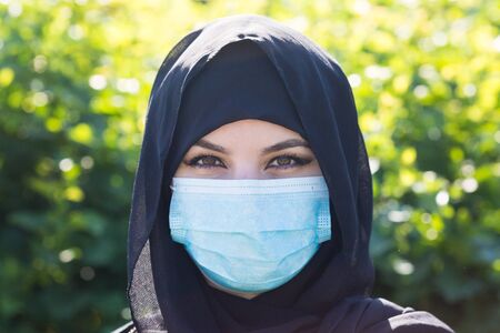 Muslim woman in medical mask. Close-up. Arab woman in a black scarf on her head in a protective medical mask. Control of proliferation and protection against corono virus 19の写真素材