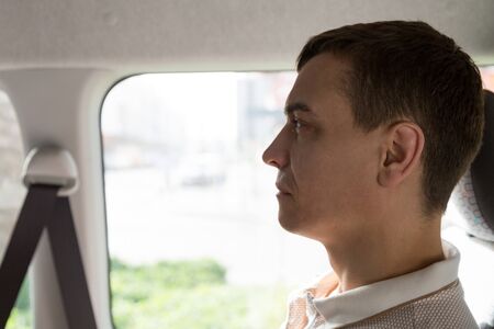Passenger public transport in Europe. A 30-35 year old man sits in a taxi near the window.