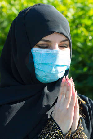 Muslim girl a protective medical mask prays to God during self-isolation and viral quarantine.の写真素材