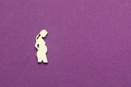Silhouette of a figure of a pregnant woman on a purple background.
