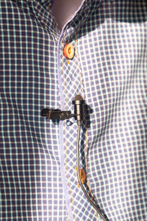 Correspondent attaches a lavalier microphone to a checked shirt.の写真素材