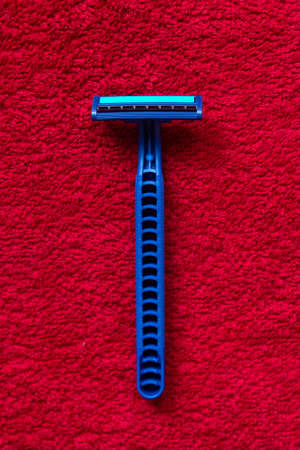 The blue razor lies on the red cloth. Deep texture.の写真素材