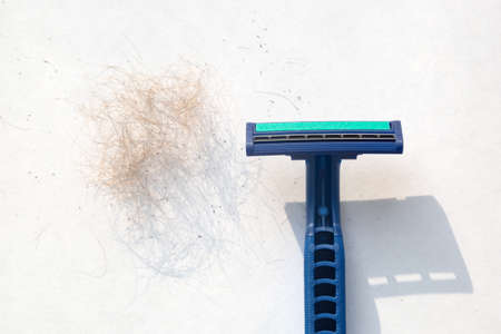Men's blue razor and a mountain of shaved hair on a white background.