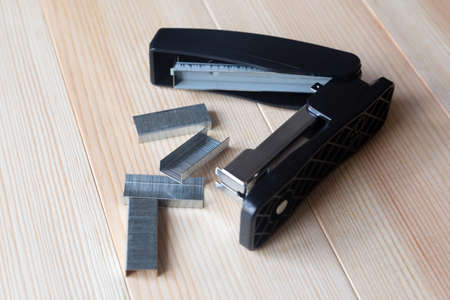 A set of office supplies. Stapler and staples wood background.