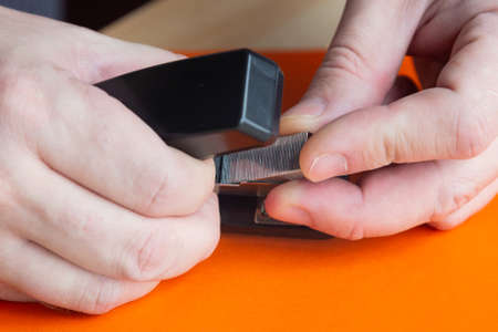 Installing clamp staples in stationery stapler. Close-up