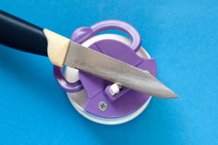 Kitchen knife and compact knife sharpener blue background.の写真素材