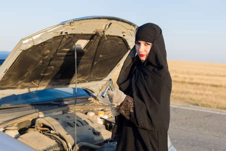 Islamic woman repairing car engine open hood.