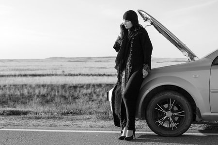 Portrait of a muslim woman calling on the phone near the car. Black and white imageの写真素材
