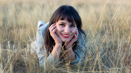 Cheerful brunette woman lies on grass in the steppe.の写真素材