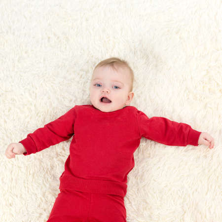 The child laughs while lying his back and looks at his parents.