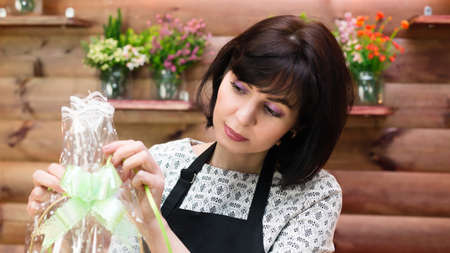 Girl florist ties the packaging of bouquet of flowers.の写真素材