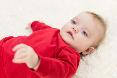 Caucasian baby red clothes lies on his back.の写真素材