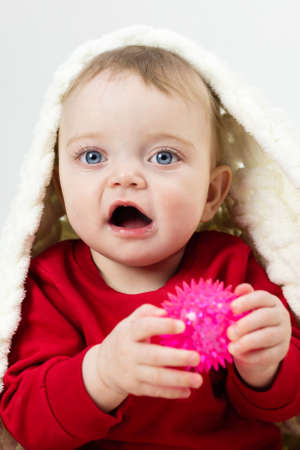 Caucasian half-year-old child playing with toy hiding with his head under the blanket.