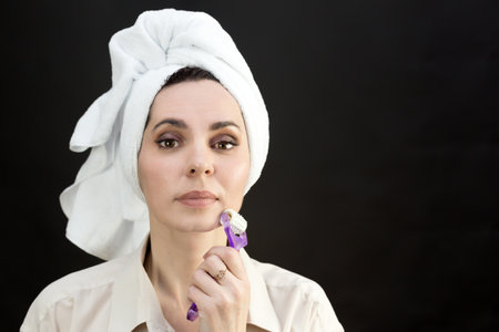 An adult woman smoothes wrinkles on her face after a bath.の写真素材