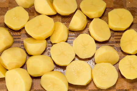 Coarsely chopped potatoes for cooking on wood board.の写真素材