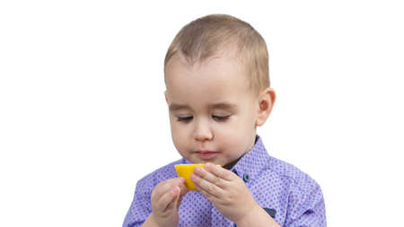 Preschool boy eating sour lemon isolated white background.の写真素材