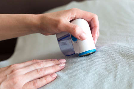 Apparatus for removing pellets from clothes in the hands of a woman, close-up.