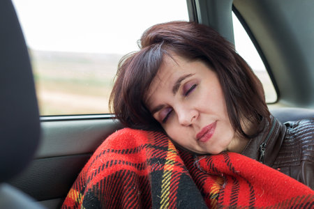 Car passenger sleeps in back seat near the window.
