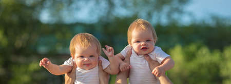 Parents play toss their twin children over their heads.