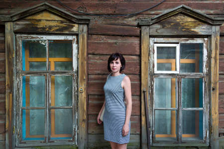 A brunette woman stands in an old wooden abandoned building.の写真素材