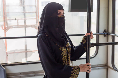 A Muslim woman in national clothes rides around the city on public transport.