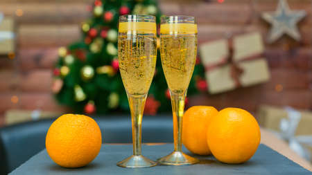 Two glasses of champagne and bright juicy oranges on the background of an elegant Christmas tree, the concept of the new year.の写真素材