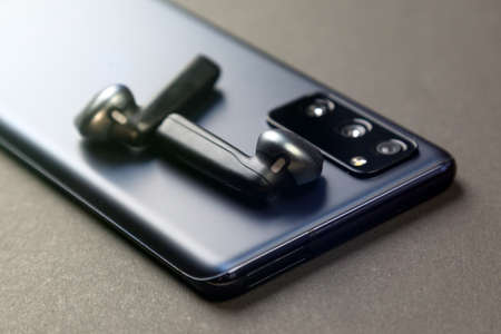 Small size wireless audio headphones lie on the smartphone.