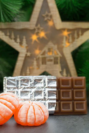 Handmade soap in the form of a bright juicy tangerine and a chocolate bar on the background of a wooden Christmas starの写真素材